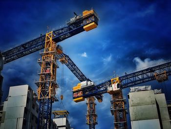 Low angle view of crane at construction site against sky