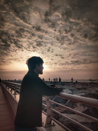 Woman looking at sea against sky during sunset