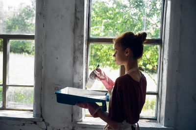 Rear view of woman looking through window