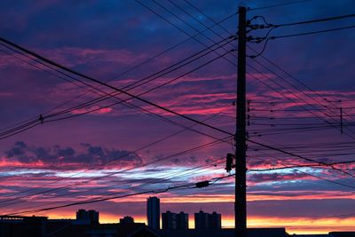 Silhouette electricity pylon against dramatic sky during sunset