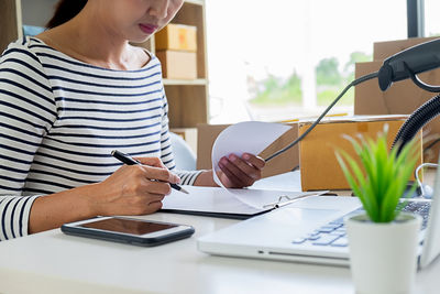 Midsection of woman using laptop on table