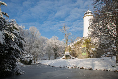 Snow covered plants by building against sky