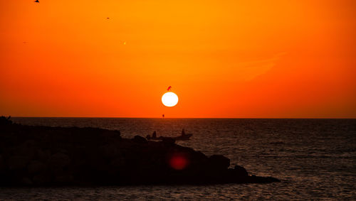 Scenic view of sea against orange sky