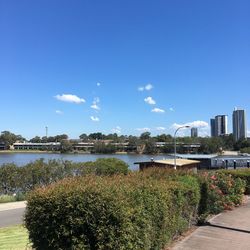 Scenic view of river by buildings against blue sky