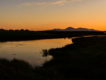 Scenic view of lake against sky during sunset