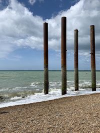 Wooden posts on beach against sky