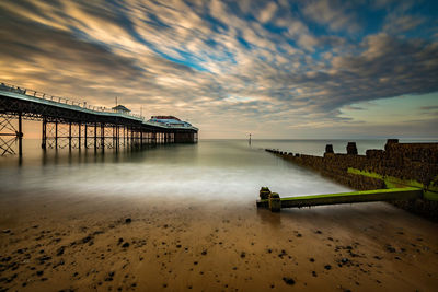 Pier over sea against sky during sunset