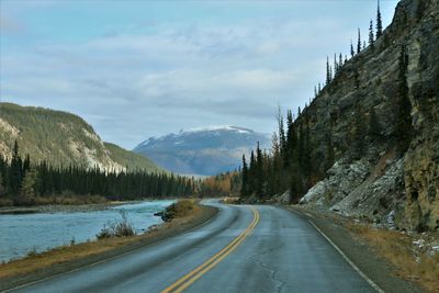 Empty road by mountains against sky