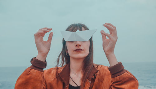 Close-up of woman with paper boat on face