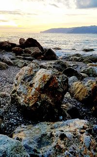 Rocks on beach against sky during sunset