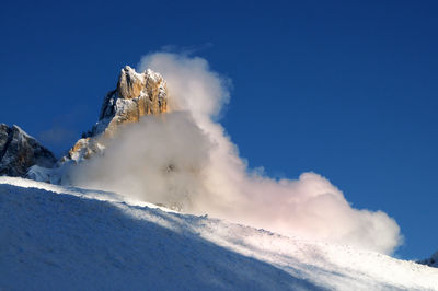 Low angle view of snow mountains against blue sky