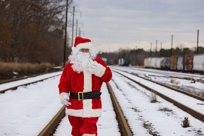 Portrait of santa standing on snow covered railroad tracks