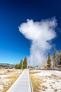 Steam emitting from landscape against blue sky