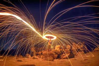 Man spinning wire wool at beach during night