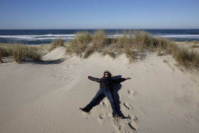 High angle view of man lying down at beach against sky