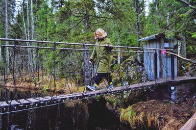 Woman walking on footbridge in forest