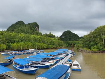 Panoramic view of boats moored on shore against sky