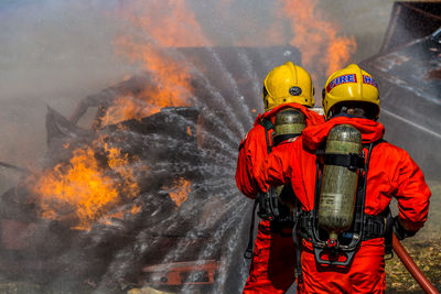 Rear view of firefighters spraying water