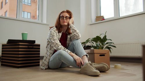 Full length of woman sitting on floor at home