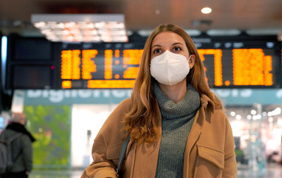 Business woman wearing face mask ffp2 kn95 at train station and keeping social distance