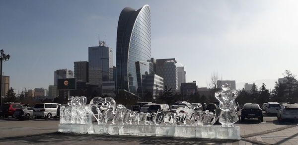 Fountain by buildings against sky in city