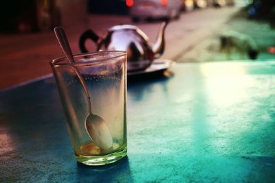 Close-up of spoon in glass on table against street