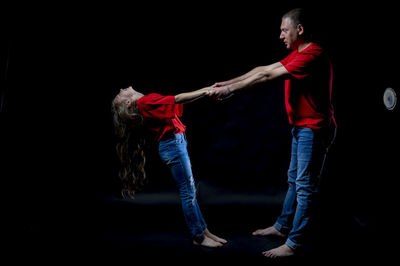 Side view of couple standing against black background