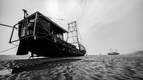 Fishing boat on beach against sky