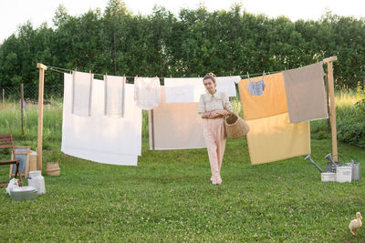 Laundry day. a woman hangs linen and towels on a tree in the courtyard of a village house.