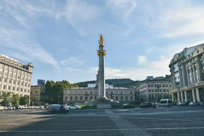 View of city street against cloudy sky