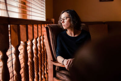 Young woman looking away while sitting outdoors