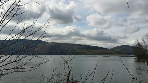 Scenic view of lake and mountains against cloudy sky