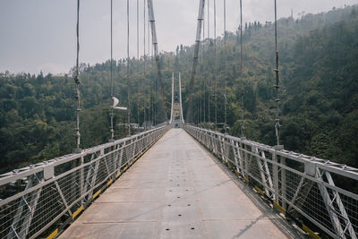 Bridge in forest against sky