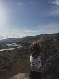 Rear view of woman standing on mountain against sky