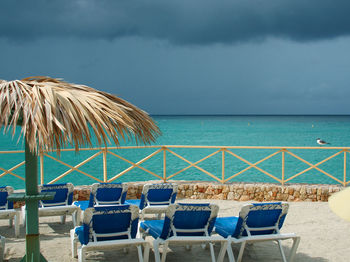 Deck chairs on beach against sky