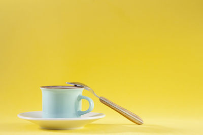 Coffee cup on table against yellow background