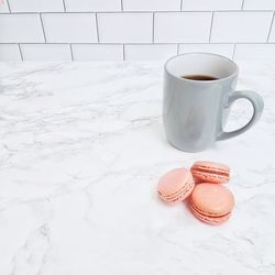High angle view of coffee cup with macaroons on table