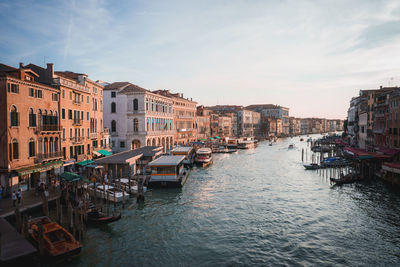 Boats in canal in city against sky