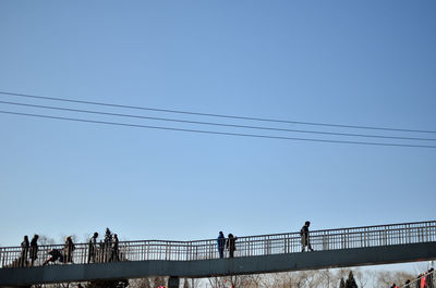 Low angle view of people against clear blue sky