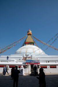 People in front of building against clear sky