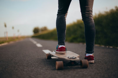 Woman stands on a longboard one space, poster, banner, anonymous photography. faceless . sunny day