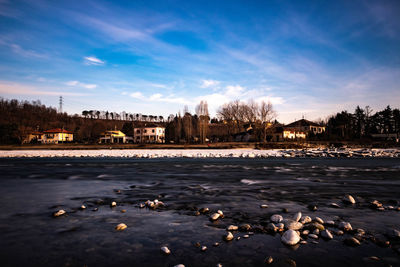 Scenic view of river by buildings against sky