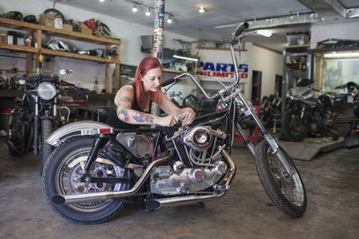 A young woman repariing a motorcycle.