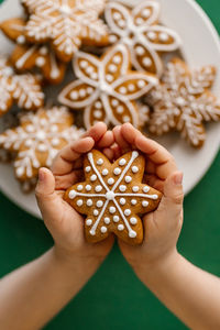 Ginger christmas cookies in children's hands on the background of the christmas tree.