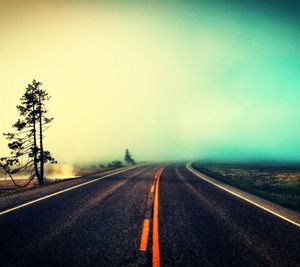 Empty road leading towards dramatic sky