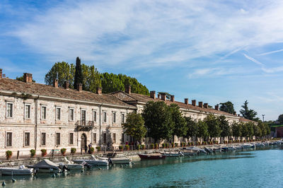 Buildings by river against sky