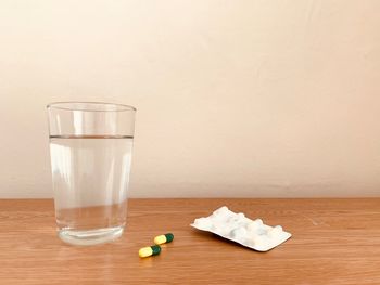 Water in glass on table with medicine capsules