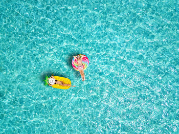 High angle view of man and woman relaxing on inflatable raft in swimming pool