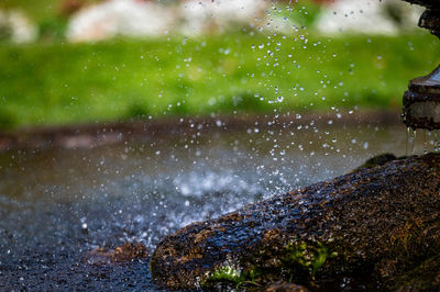 Closeup view of water splashing over a rock in a pool under a fountain, selective focus