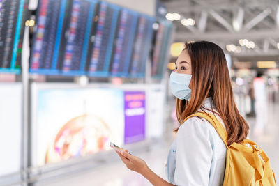 Woman wearing mask using mask standing at airport